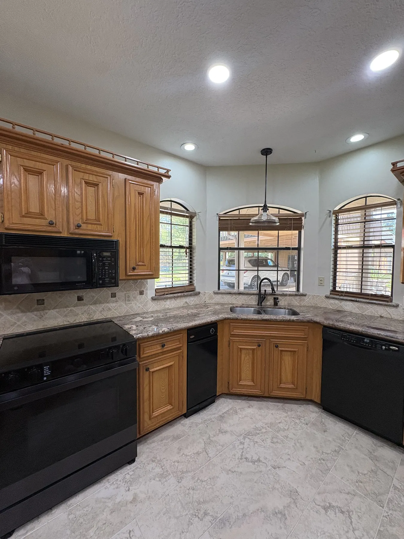 Honey-oak kitchen cabinets, granite counters, and arched windows before refinishing